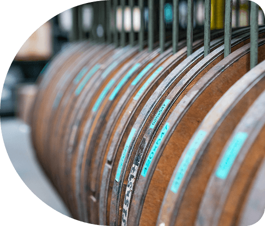 A row of wooden barrels with blue labels lined up in a storage area.
