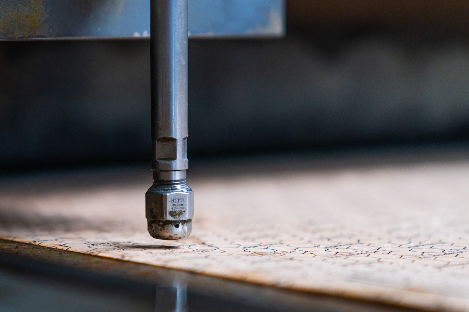 Close-up of a waterjet cutter nozzle cutting intricate patterns on a sheet of material.